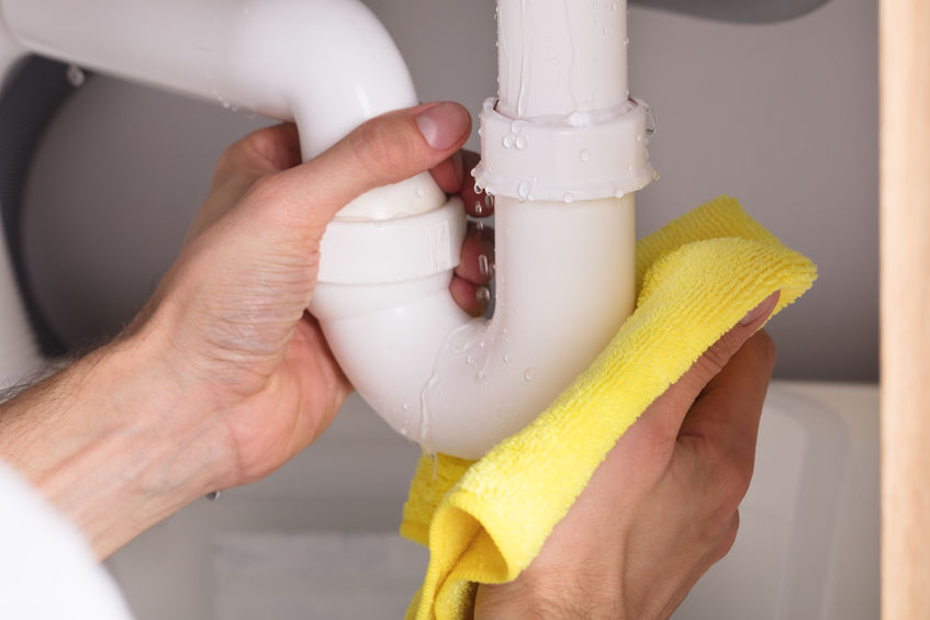 Close-up Of A Person's Hand Holding Yellow Napkin Under Sink Pipe Leakage