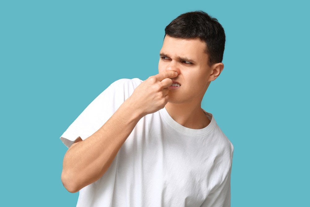 person pinching their nose while looking at a smelly drain