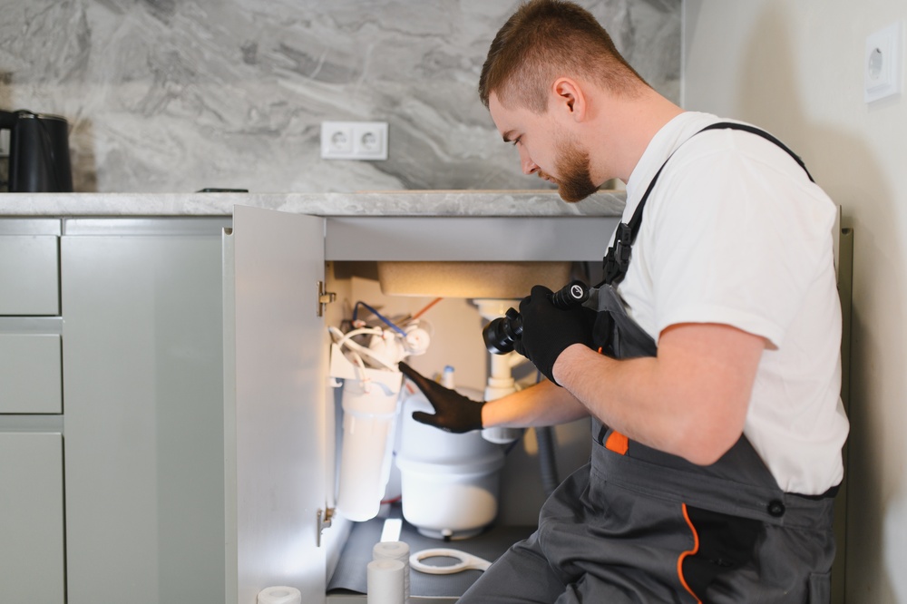 Plumber performing maintenance on a complex under sink water filtration system