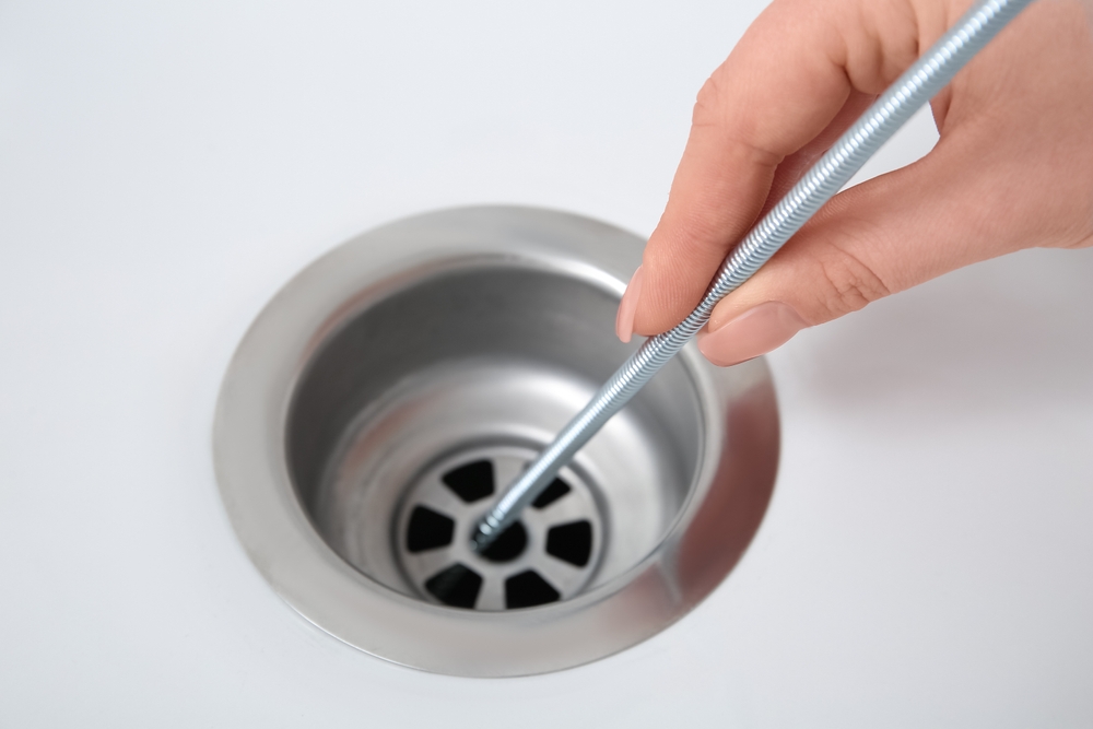 woman-cleaning-drain-plumbers-snake-closeup