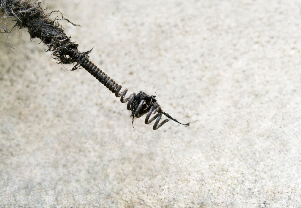 plumbing snake pulling clogged hair from drain