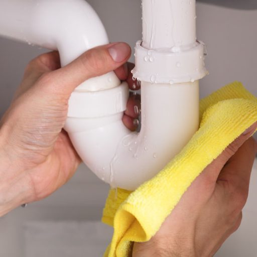 Close-up Of A Person's Hand Holding Yellow Napkin Under Sink Pipe Leakage