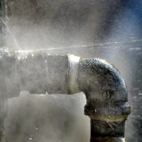 Old rusty pipe with leak and water spraying out