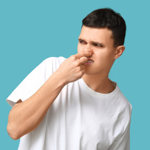 person pinching their nose while looking at a smelly drain