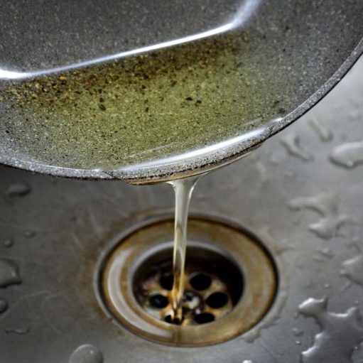 person pouring cooking oil down the kitchen sink