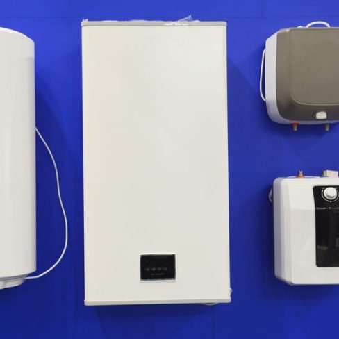 Electric boilers, water heaters display of different sizes and forms, hung on a wall in a shop for sale.