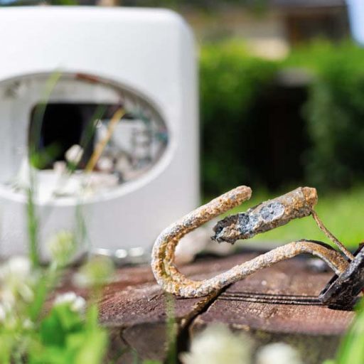 Heating element, rust and scale on boiler background, lying on wooden table. Concept of repair and maintenance of home appliances. Close up.