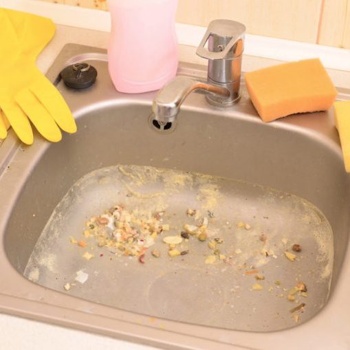 Close up on dirty clogging kitchen sink drain. Blur and selective focus of sink hole clogging up with food particles